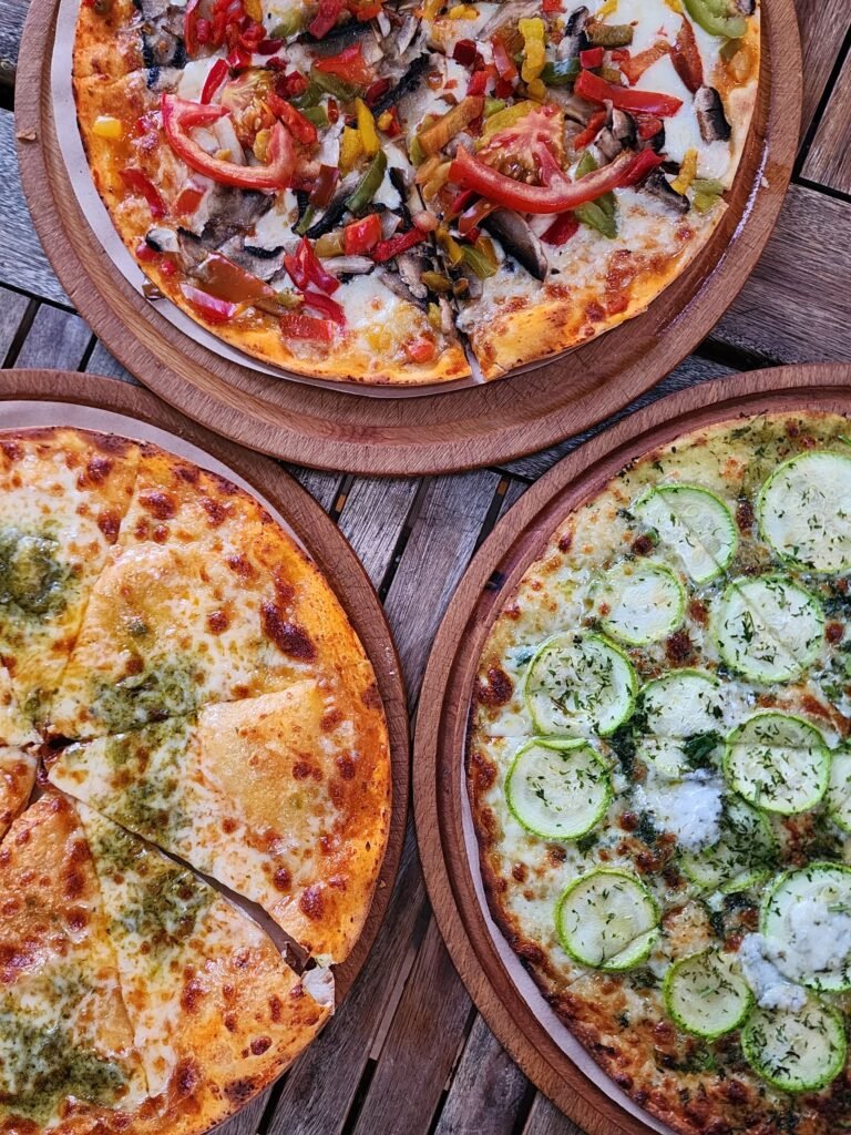 Pizzas with Various Toppings Served on Wooden Plates