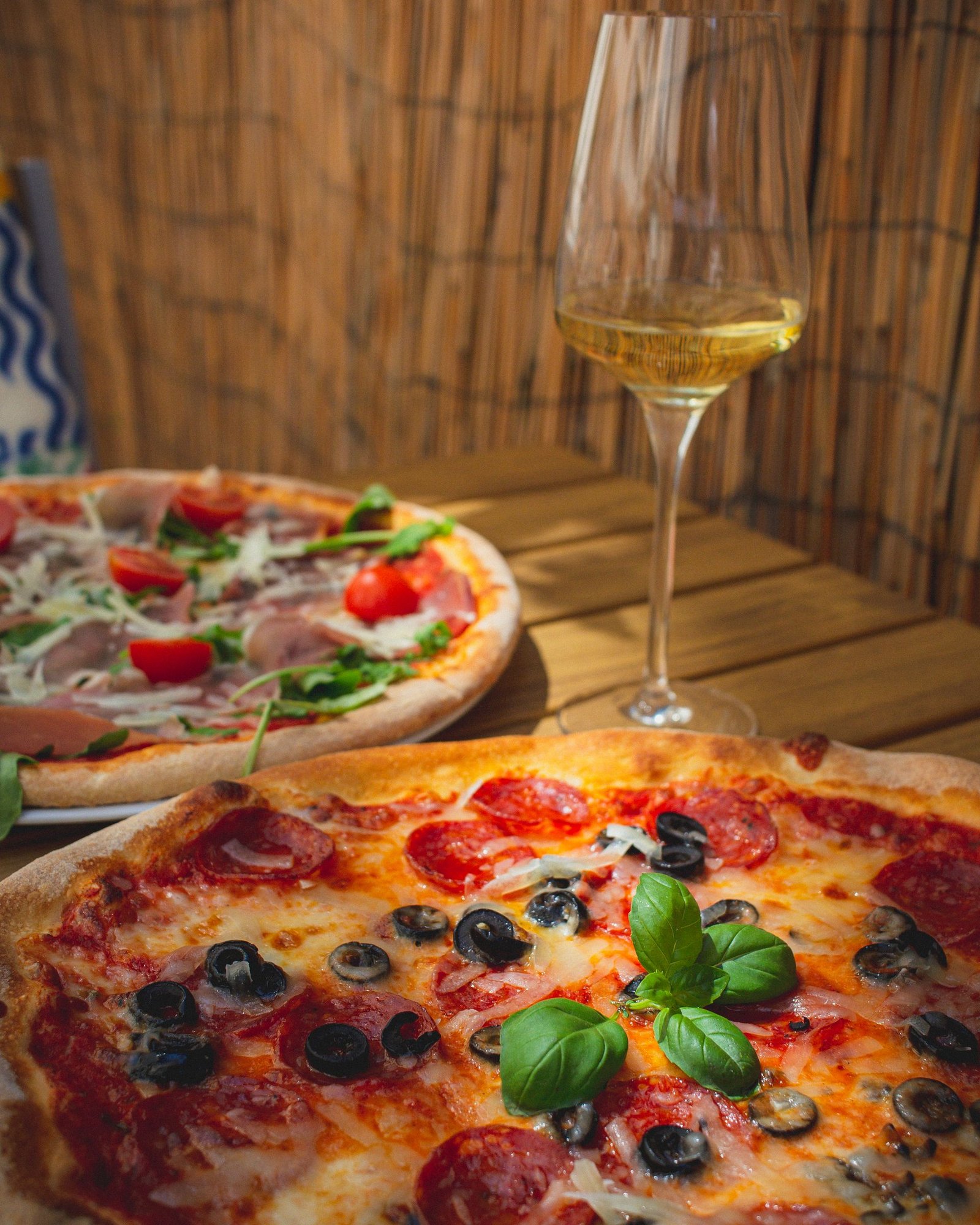 Pizzas and Wine Glass on Table