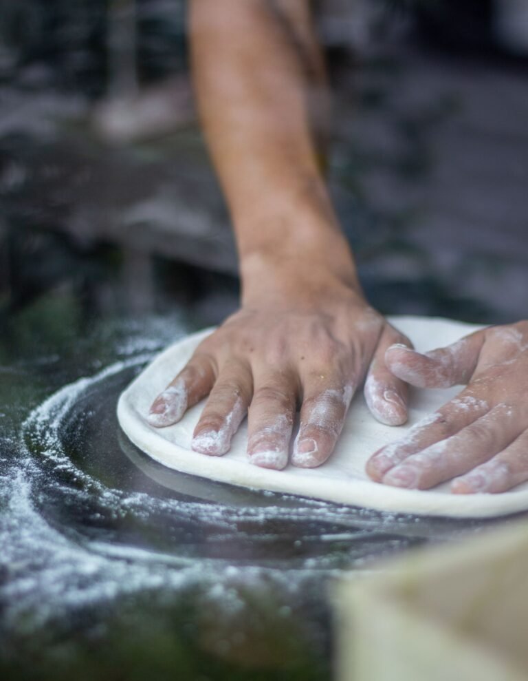 A Persons Spreading Flour on a Dough