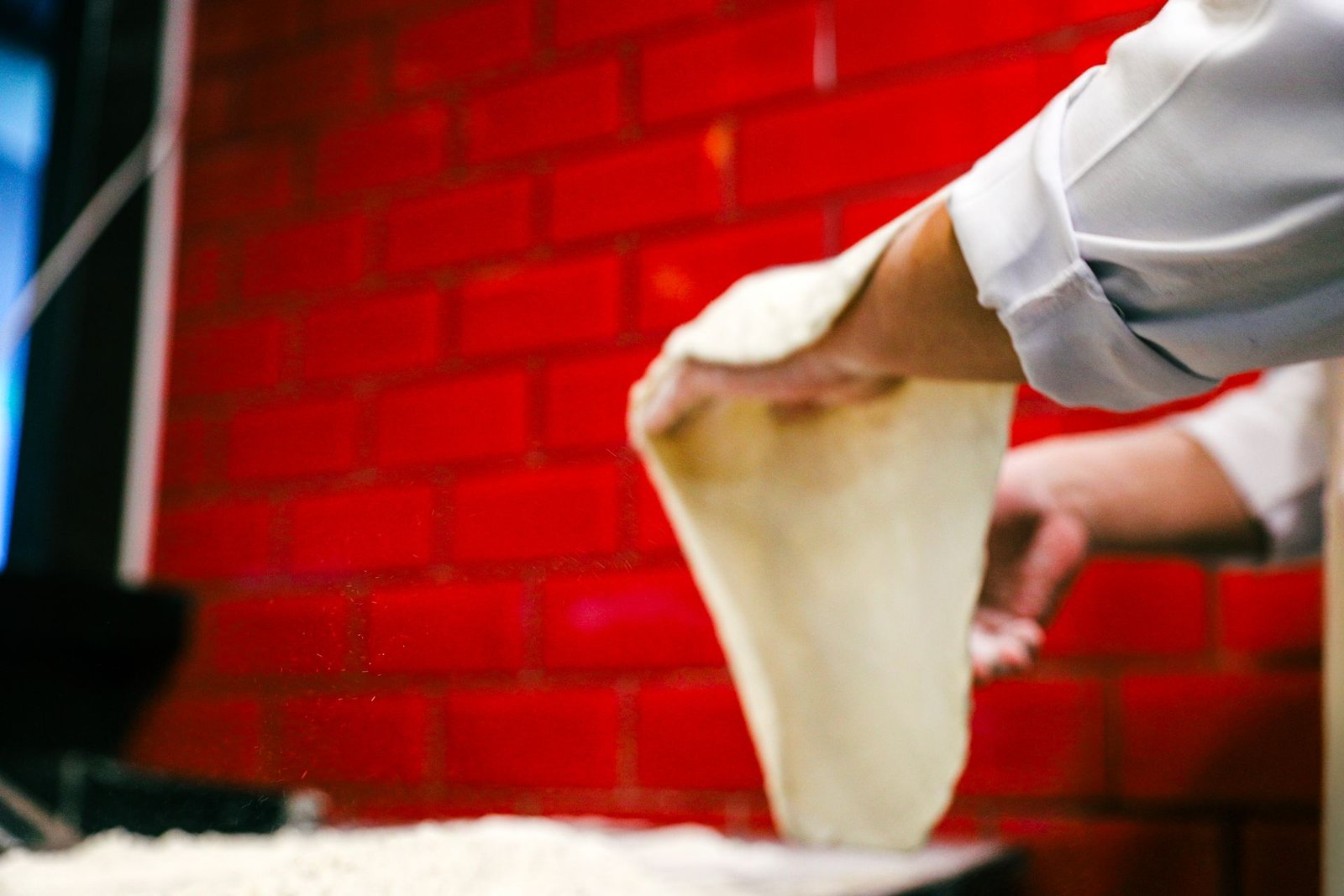 Chef Stretching Pizza Dough in Rustic Kitchen