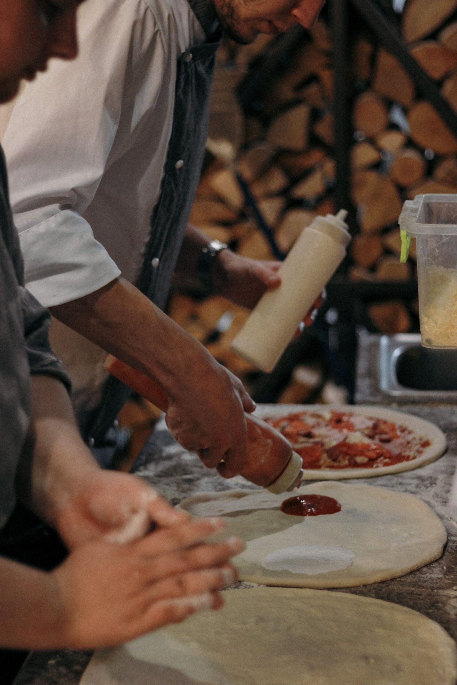 Person Putting Tomato Sauce on a Round Dough
