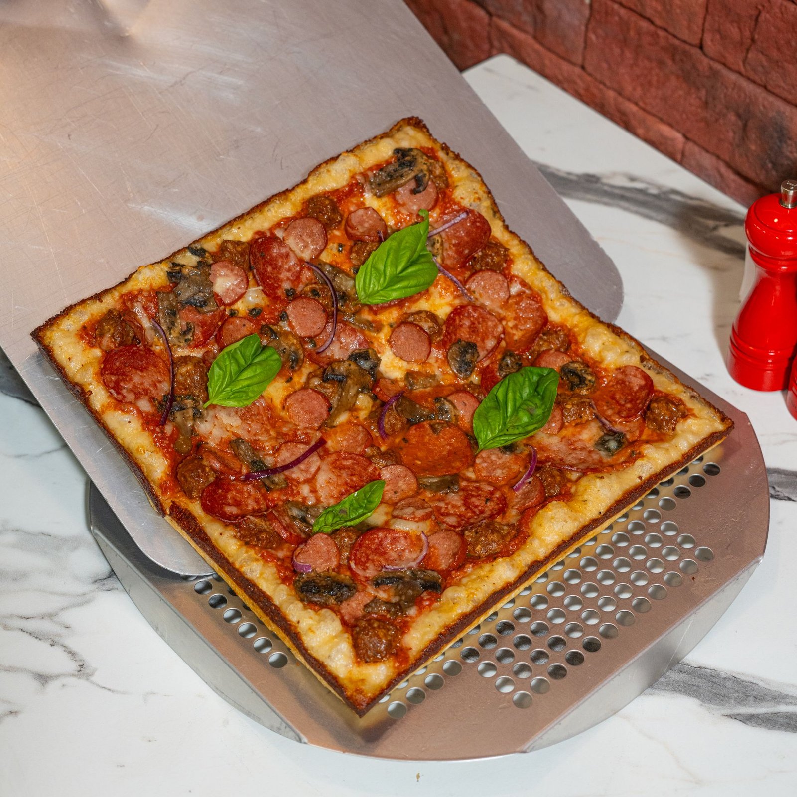Square Pepperoni Pizza with Basil Leaves on Pizza Peel