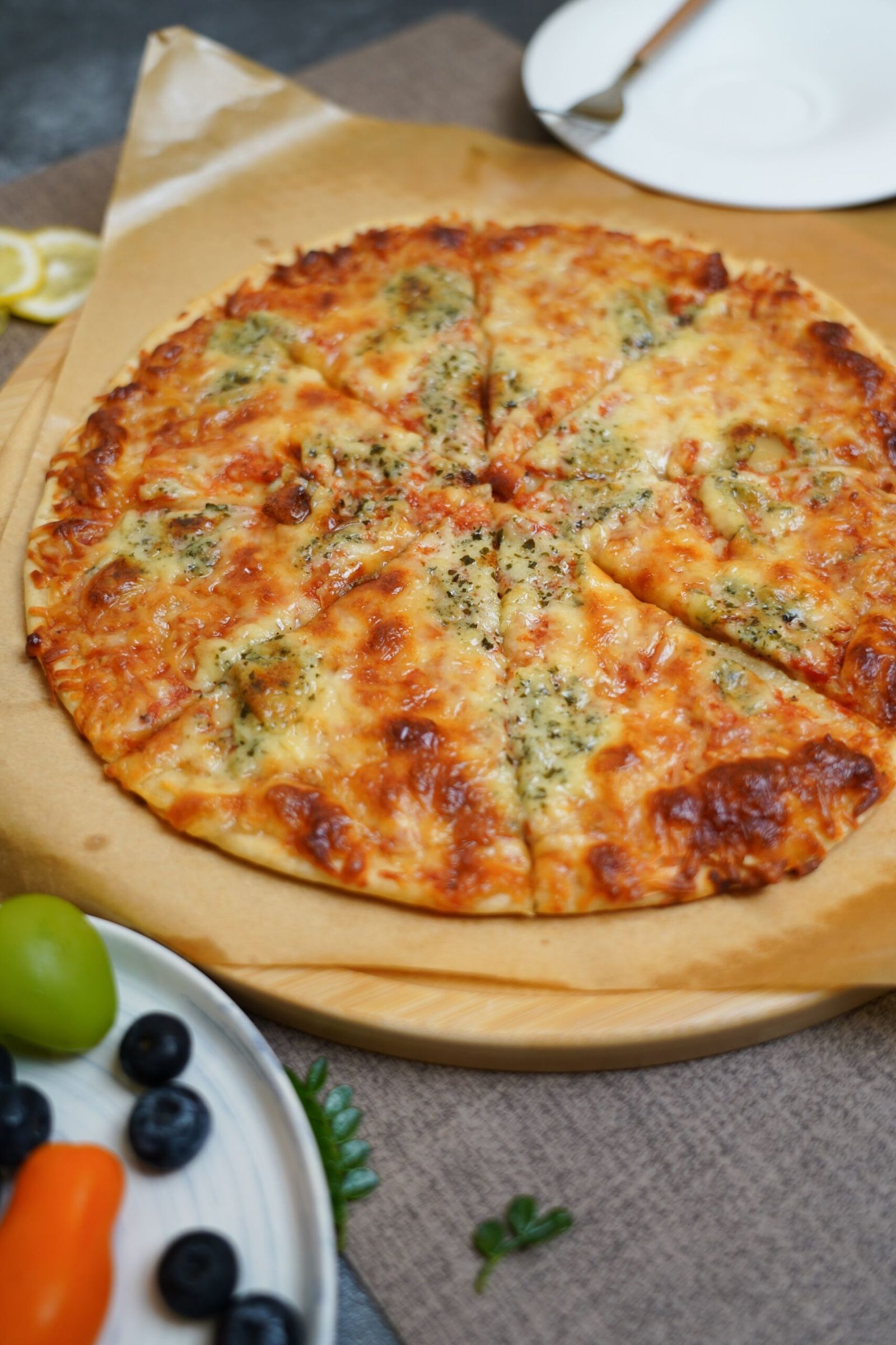 A pizza with cheese and vegetables on a wooden board