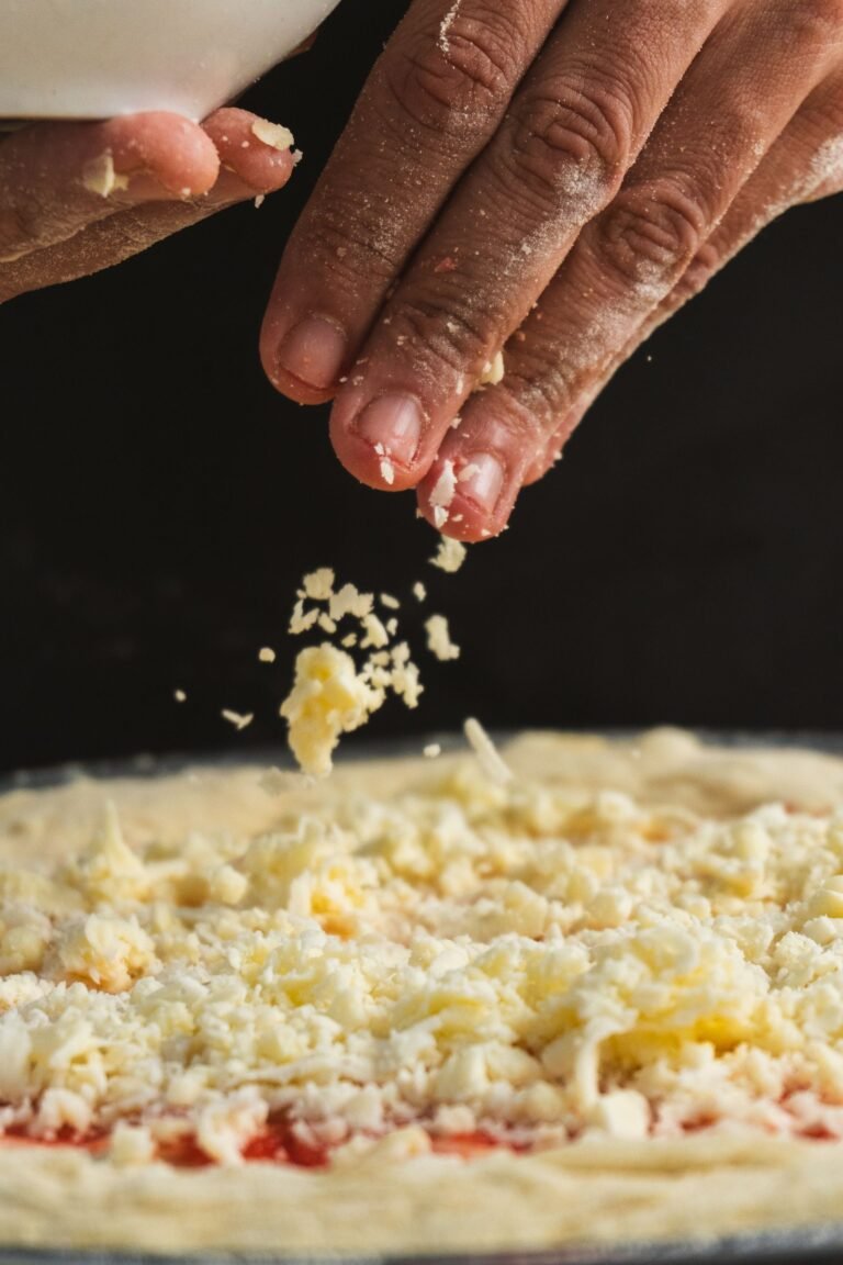 Close-up of Cheese Being Spread on Pizza Dough