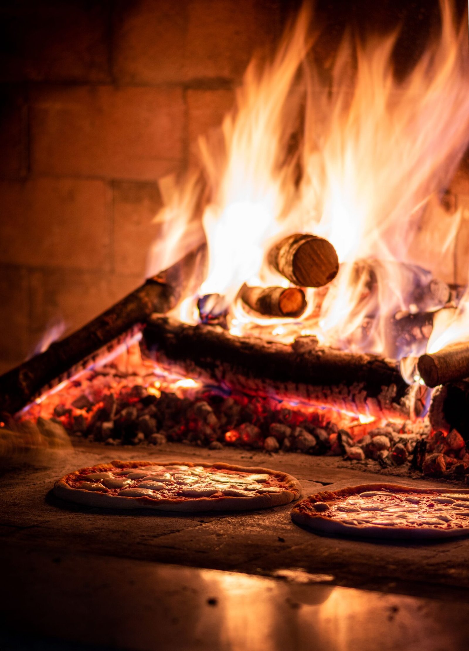 Pizzas in a stone oven with a fire