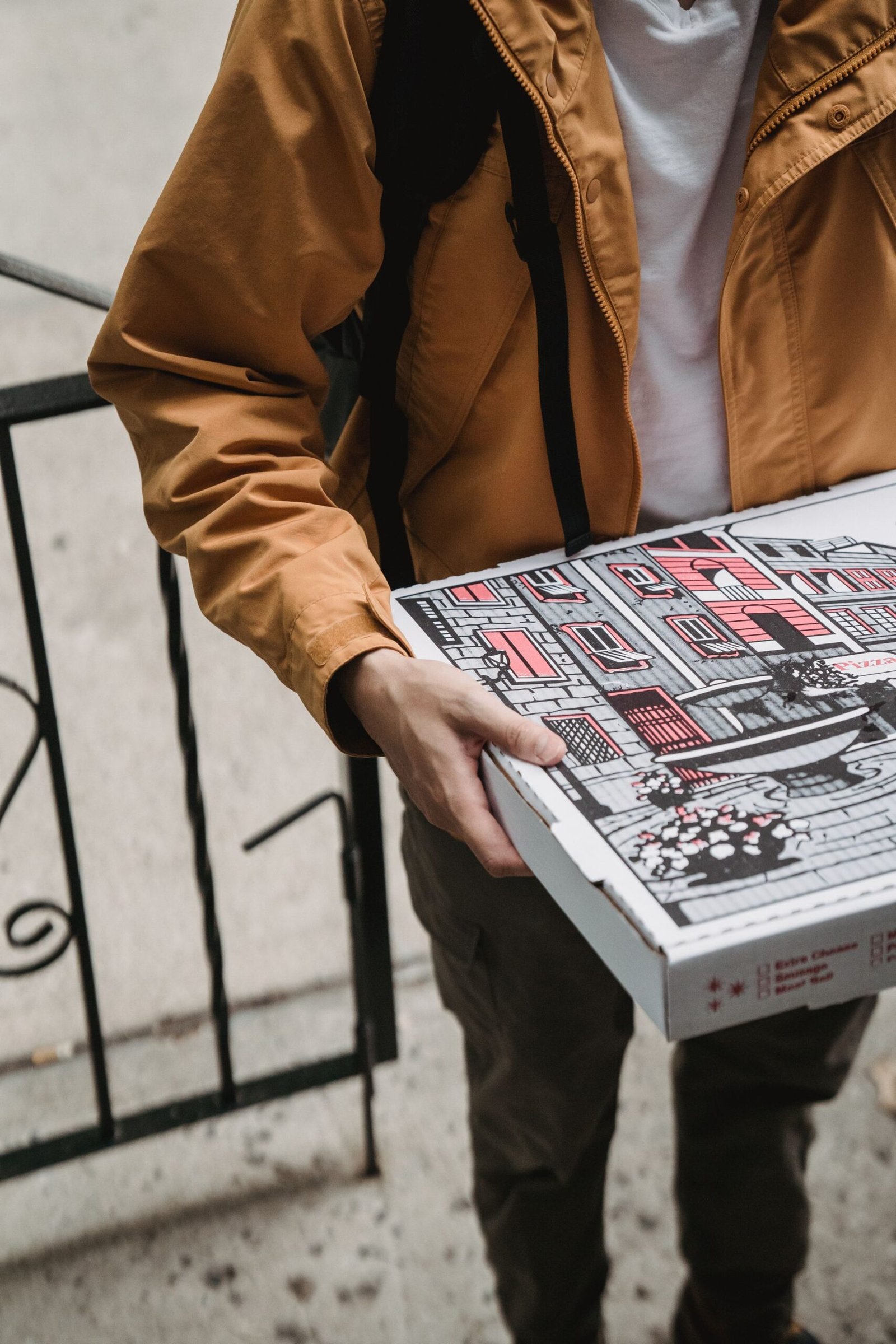 Person in Brown Jacket Delivering Pizza