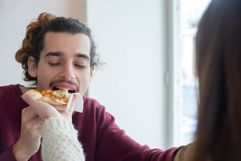 A Person Feeding a Man Pizza