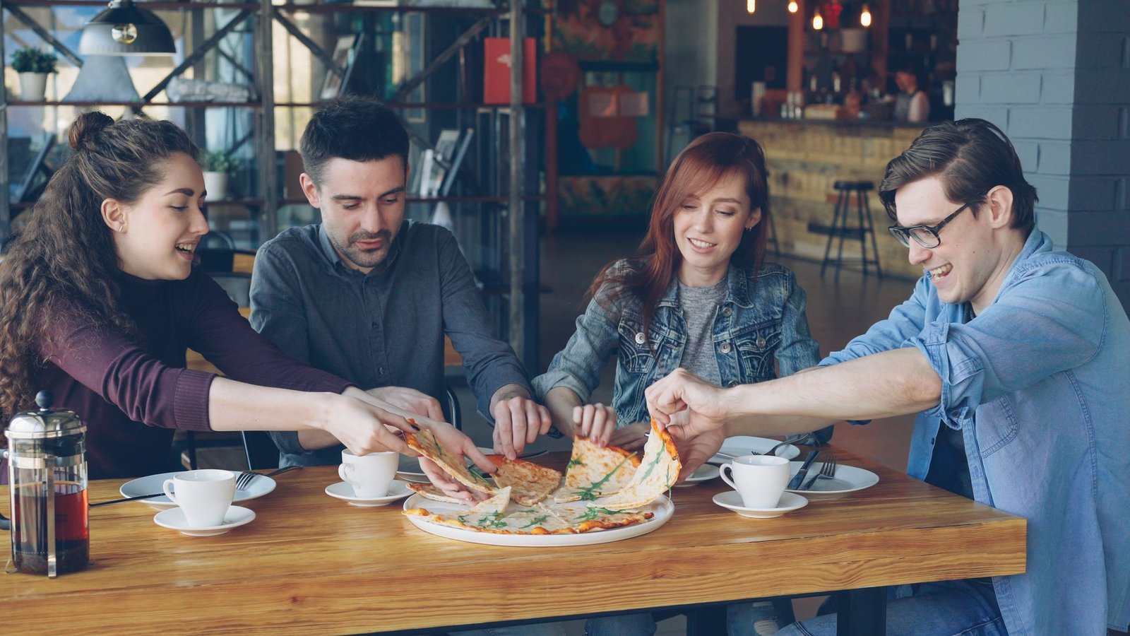 Friends Enjoying Pizza in a Cozy CafÃ©