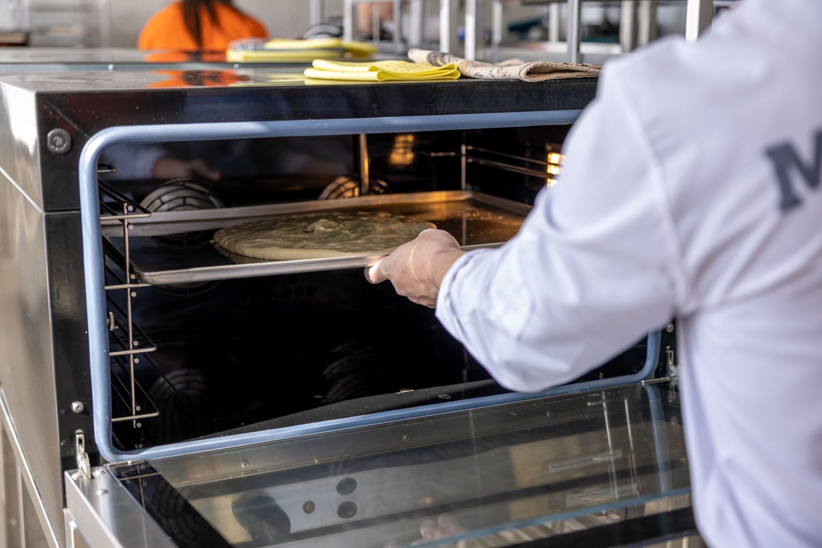 Chef placing pizza in industrial oven