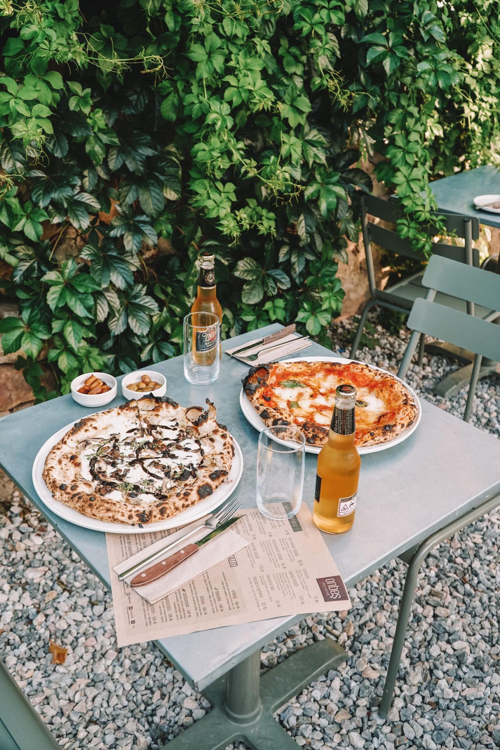 Delicious Pizzas on Table with a Pair of Cold Bottles of Beers 