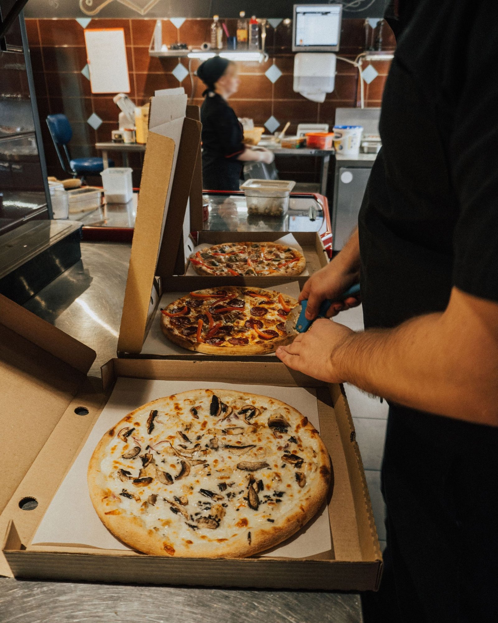 Person Slicing the Pizzas