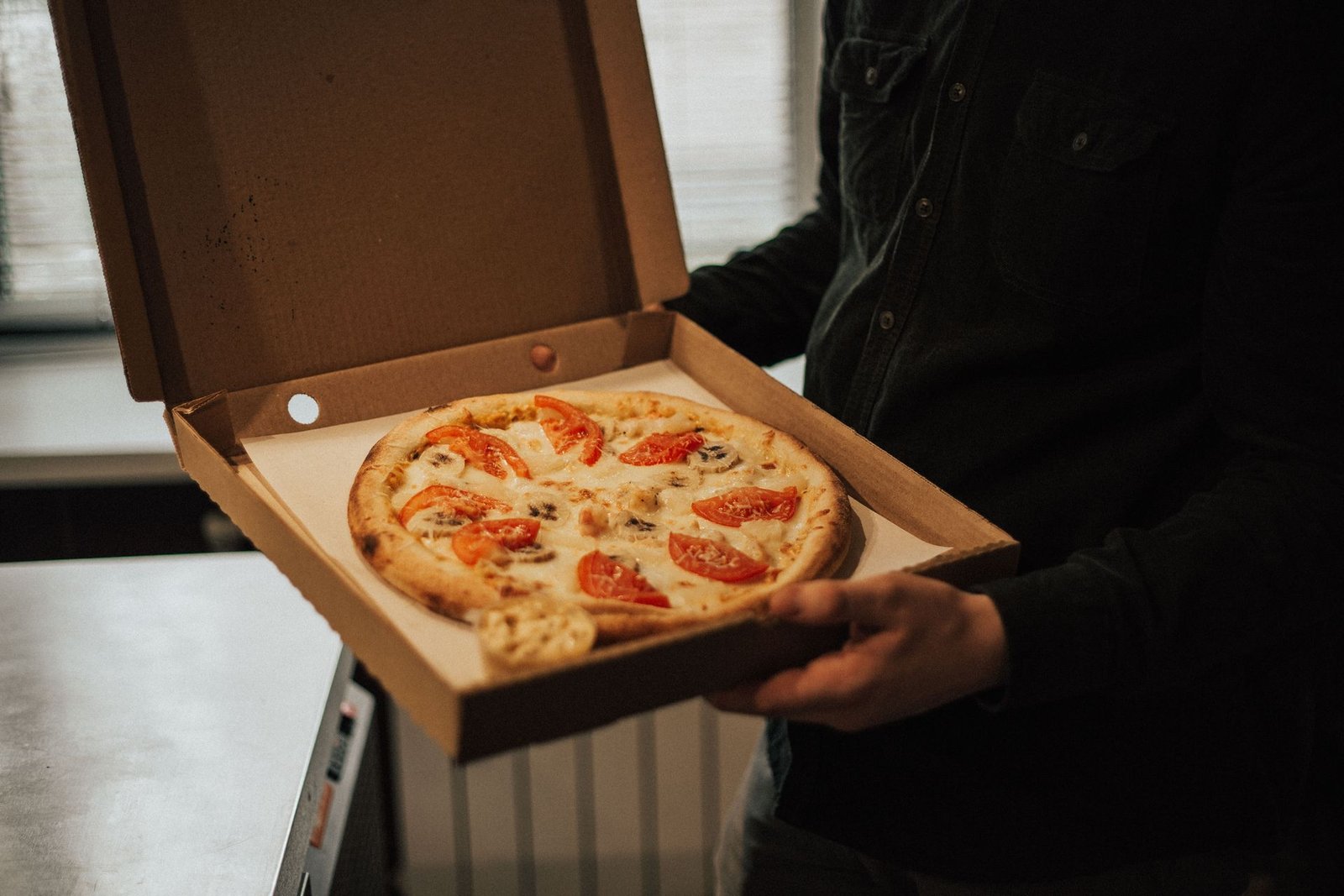Person Holding a Pizza in Box
